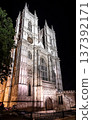 Historic gothic cathedral architecture illuminated at night under a dramatic sky, highlighting intricate stone design and timeless European heritage. 137392171