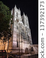 Historic gothic cathedral architecture illuminated at night under a dramatic sky, highlighting intricate stone design and timeless European heritage. 137392173