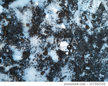 Top view of dark soil ground covered with melting white snow. Winter texture background 137392550