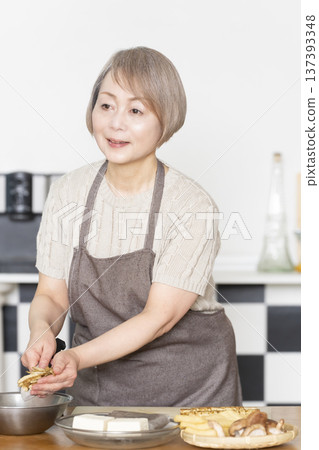 Senior woman cutting vegetables and preparing food in the kitchen Senior woman cutting vegetables and preparing food in the kitchen 137393348