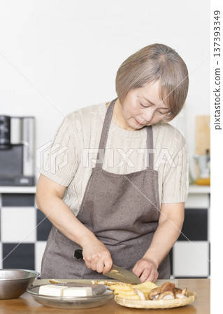 Senior woman cutting vegetables and preparing food in the kitchen Senior woman cutting vegetables and preparing food in the kitchen 137393349