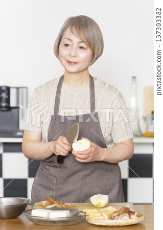 Senior woman cutting vegetables and preparing food in the kitchen Senior woman cutting vegetables and preparing food in the kitchen 137393382