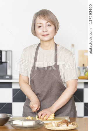 Senior woman cutting vegetables and preparing food in the kitchen Senior woman cutting vegetables and preparing food in the kitchen 137393400