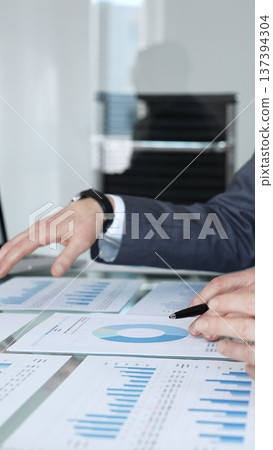 Business people reviewing and negotiating contract terms in an office meeting, focusing on agreement details and legal paperwork before signing Business people reviewing and negotiating contract terms in an office meeting, focusing on agreement details and legal paperwork before signing 137394304