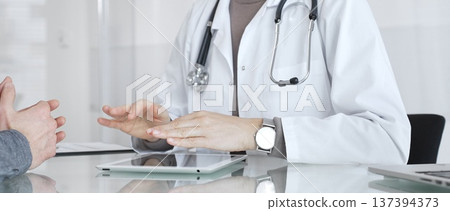 Doctor consulting patient, discussing diagnosis, using digital tablet in modern medical clinic. Medicine and health care Doctor consulting patient, discussing diagnosis, using digital tablet in modern medical clinic. Medicine and health care 137394373