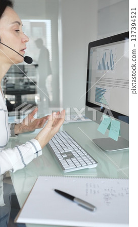 Female call center agent wearing a headset, assisting customers remotely and participating in a virtual office meeting. Professional customer support and business services Female call center agent wearing a headset, assisting customers remotely and participating in a virtual office meeting. Professional customer support and business services 137394521