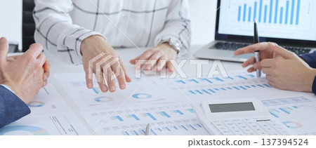 Business people discussing financial data and analyzing market trends during a corporate meeting, reviewing strategy with charts and graphs in the office Business people discussing financial data and analyzing market trends during a corporate meeting, reviewing strategy with charts and graphs in the office 137394524