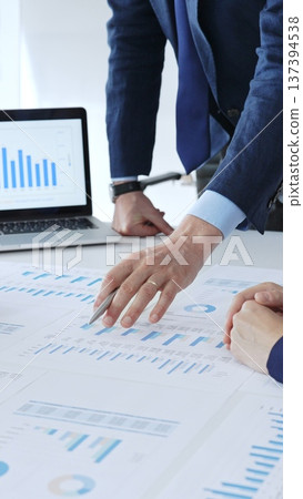 Businessman standing above the table and pointing into financial charts while discussing financial data, market trends during a corporate meeting in office. Business people concept Businessman standing above the table and pointing into financial charts while discussing financial data, market trends during a corporate meeting in office. Business people concept 137394538