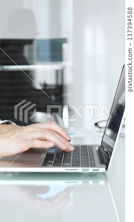 Hands expertly typing on a laptop keyboard, a professional working on important business tasks and digital communication in a modern, clean office environment 137394588