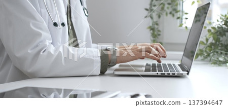 Medical professional wearing white lab coat typing on laptop, documenting patient information with clinical precision at workstation. Medicine and health care concept Medical professional wearing white lab coat typing on laptop, documenting patient information with clinical precision at workstation. Medicine and health care concept 137394647