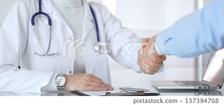 A doctor and patient shaking hands, building trust and understanding during a medical consultation. Healthcare, compassion, and professionalism concept A doctor and patient shaking hands, building trust and understanding during a medical consultation. Healthcare, compassion, and professionalism concept 137394708