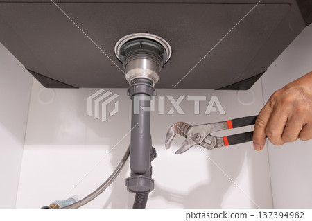 Plumber open trap to fixing drain clog under sink. Plumber open trap to fixing drain clog under sink. 137394982