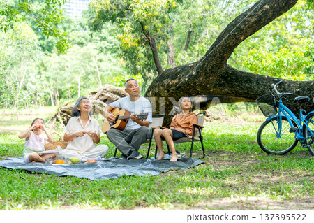 Asian grandfather and grandmother and two girls in public park look up to the tree to look for lovely animal such as bird or squirrel. 137395522