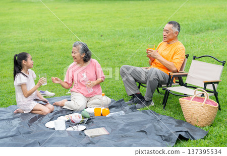 High view of Asian grandmother, grandfather and grandchild enjoy to relax with family together in public park with day light and they look happiness with smiling High view of Asian grandmother, grandfather and grandchild enjoy to relax with family together in public park with day light and they look happiness with smiling 137395534