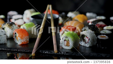 Colorful variety of sushi served on slate platter with chopsticks placed next to it in a dining setting during evening hours Colorful variety of sushi served on slate platter with chopsticks placed next to it in a dining setting during evening hours 137395816