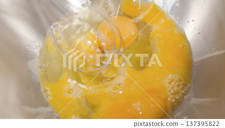 Mixing eggs in a bowl for cooking in a kitchen setting during daytime hours 137395822