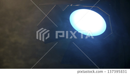 Spotlight shines brightly in a dimly lit room during a performance in the evening hours Spotlight shines brightly in a dimly lit room during a performance in the evening hours 137395831