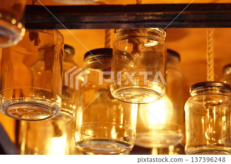 Vintage glass jars on the ceiling in the store in the evening. Light through the glass of the jar. Vintage glass jars on the ceiling in the store in the evening. Light through the glass of the jar. 137396248