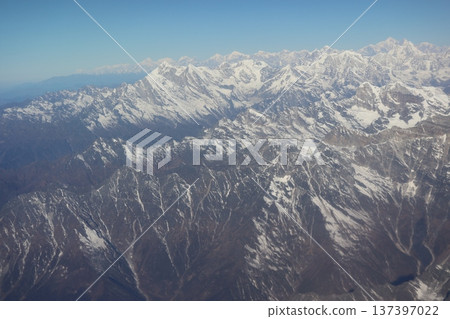 A view of the snow-capped Himalayan mountains and blue sky from the window of a mountain flight airplane 137397022