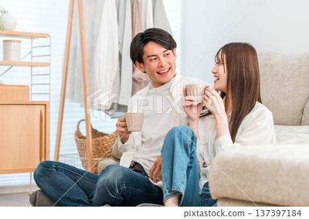 一對年輕的亞洲夫婦在家裡的客廳喝熱飲（未來規劃、人生規劃、生活方式） 137397184