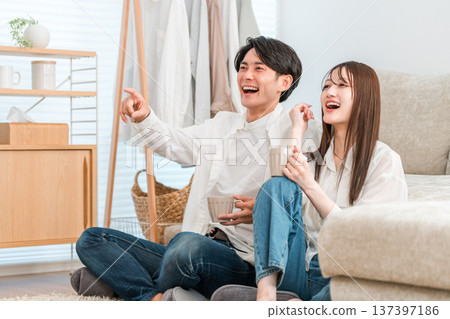 Young Asian couple watching TV in the living room at home Young Asian couple watching TV in the living room at home 137397186