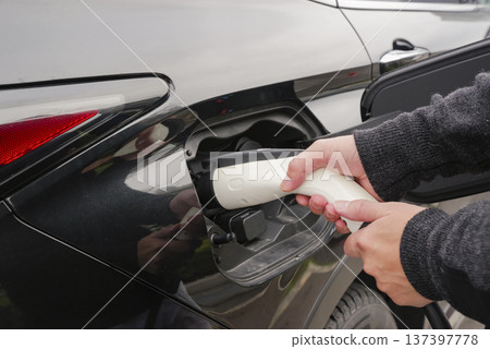 Driver's hands connecting the EV charging plug Driver's hands connecting the EV charging plug 137397778