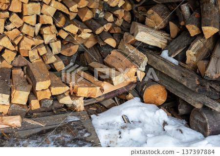 Firewood on melting snow scene. Firewood arrangement amidst melting snow with rustic textures 137397884