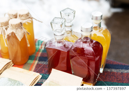 Artisan bottled beverages and syrups presented on cozy farmers market table with handwritten labels 137397897