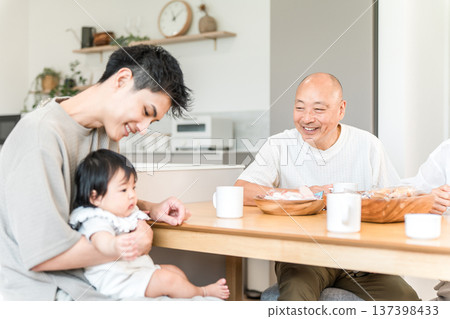 A senior man having tea with his son and grandson who have returned home 137398433