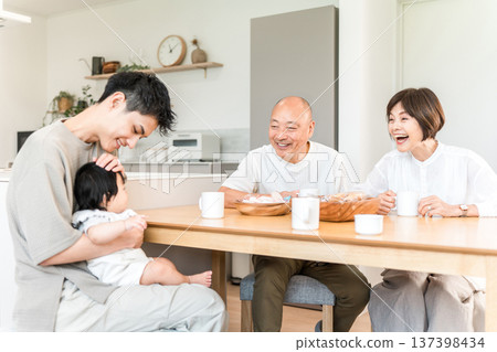 A senior couple having tea with their son and grandson who have returned home 137398434