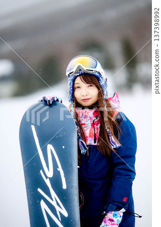 年輕女子在滑雪勝地的山坡上享受冬季運動-單板滑雪。 年輕女子在滑雪勝地的山坡上享受冬季運動-單板滑雪。 137398992