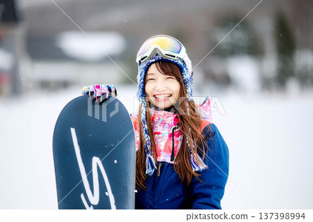 Young woman enjoying winter sports snowboarding on the slopes of a ski resort Young woman enjoying winter sports snowboarding on the slopes of a ski resort 137398994