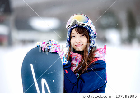 年輕女子在滑雪勝地的山坡上享受冬季運動-單板滑雪。 年輕女子在滑雪勝地的山坡上享受冬季運動-單板滑雪。 137398999