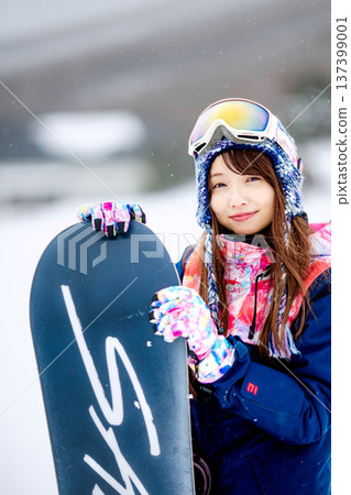 Young woman enjoying winter sports snowboarding on the slopes of a ski resort Young woman enjoying winter sports snowboarding on the slopes of a ski resort 137399001