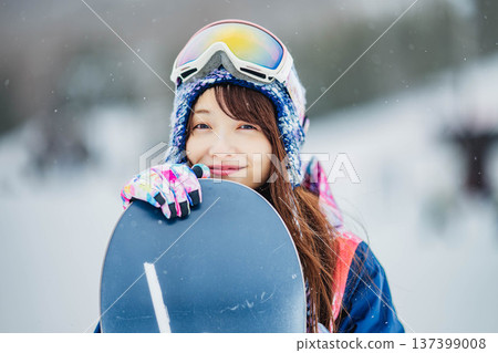 Young woman enjoying winter sports snowboarding on the slopes of a ski resort Young woman enjoying winter sports snowboarding on the slopes of a ski resort 137399008