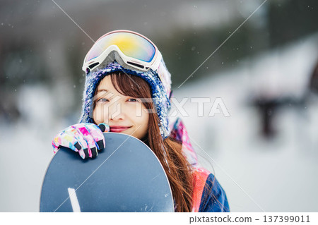 年輕女子在滑雪勝地的山坡上享受冬季運動－單板滑雪。 137399011