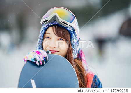 年輕女子在滑雪勝地的山坡上享受冬季運動－單板滑雪。 137399018