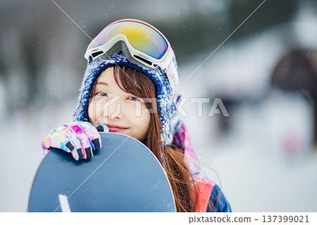年輕女子在滑雪勝地的山坡上享受冬季運動－單板滑雪。 137399021