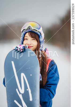 Young woman enjoying winter sports snowboarding on the slopes of a ski resort 137399024