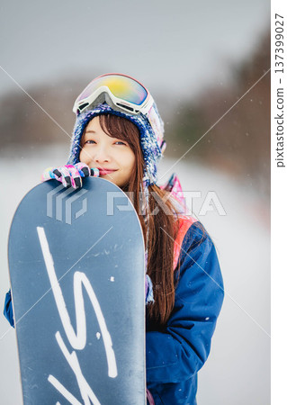 年輕女子在滑雪勝地的山坡上享受冬季運動－單板滑雪。 137399027