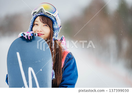 年輕女子在滑雪勝地的山坡上享受冬季運動-單板滑雪。 年輕女子在滑雪勝地的山坡上享受冬季運動-單板滑雪。 137399030
