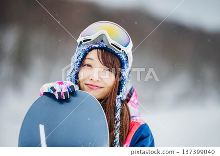Young woman enjoying winter sports snowboarding on the slopes of a ski resort Young woman enjoying winter sports snowboarding on the slopes of a ski resort 137399040