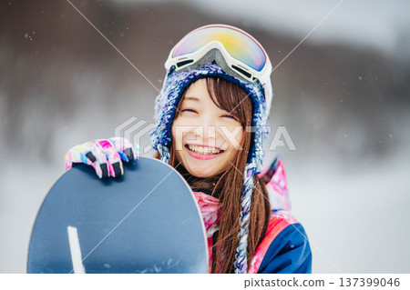 Young woman enjoying winter sports snowboarding on the slopes of a ski resort 137399046