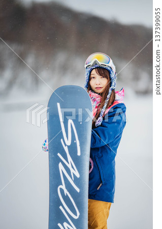 年輕女子在滑雪勝地的山坡上享受冬季運動－單板滑雪。 137399055