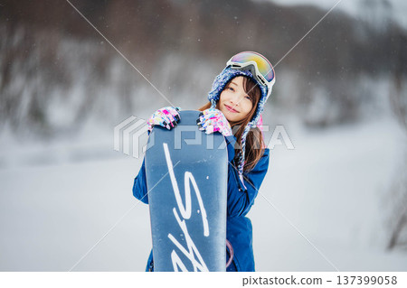 Young woman enjoying winter sports snowboarding on the slopes of a ski resort 137399058
