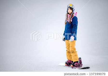 年輕女子在滑雪勝地的山坡上享受冬季運動-單板滑雪。 年輕女子在滑雪勝地的山坡上享受冬季運動-單板滑雪。 137399070