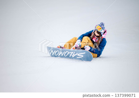 年輕女子在滑雪勝地的山坡上享受冬季運動-單板滑雪。 年輕女子在滑雪勝地的山坡上享受冬季運動-單板滑雪。 137399071