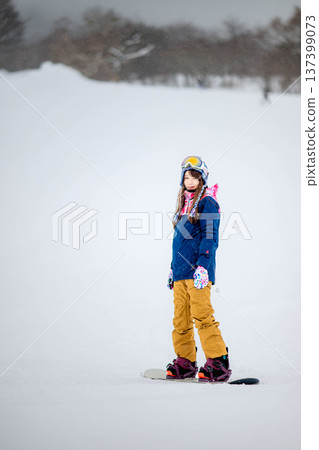 年輕女子在滑雪勝地的山坡上享受冬季運動-單板滑雪。 年輕女子在滑雪勝地的山坡上享受冬季運動-單板滑雪。 137399073