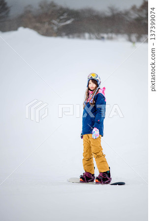 年輕女子在滑雪勝地的山坡上享受冬季運動-單板滑雪。 年輕女子在滑雪勝地的山坡上享受冬季運動-單板滑雪。 137399074