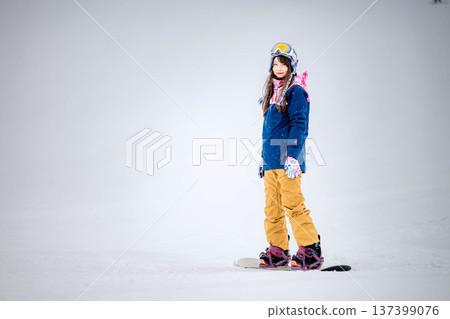 Young woman enjoying winter sports snowboarding on the slopes of a ski resort Young woman enjoying winter sports snowboarding on the slopes of a ski resort 137399076